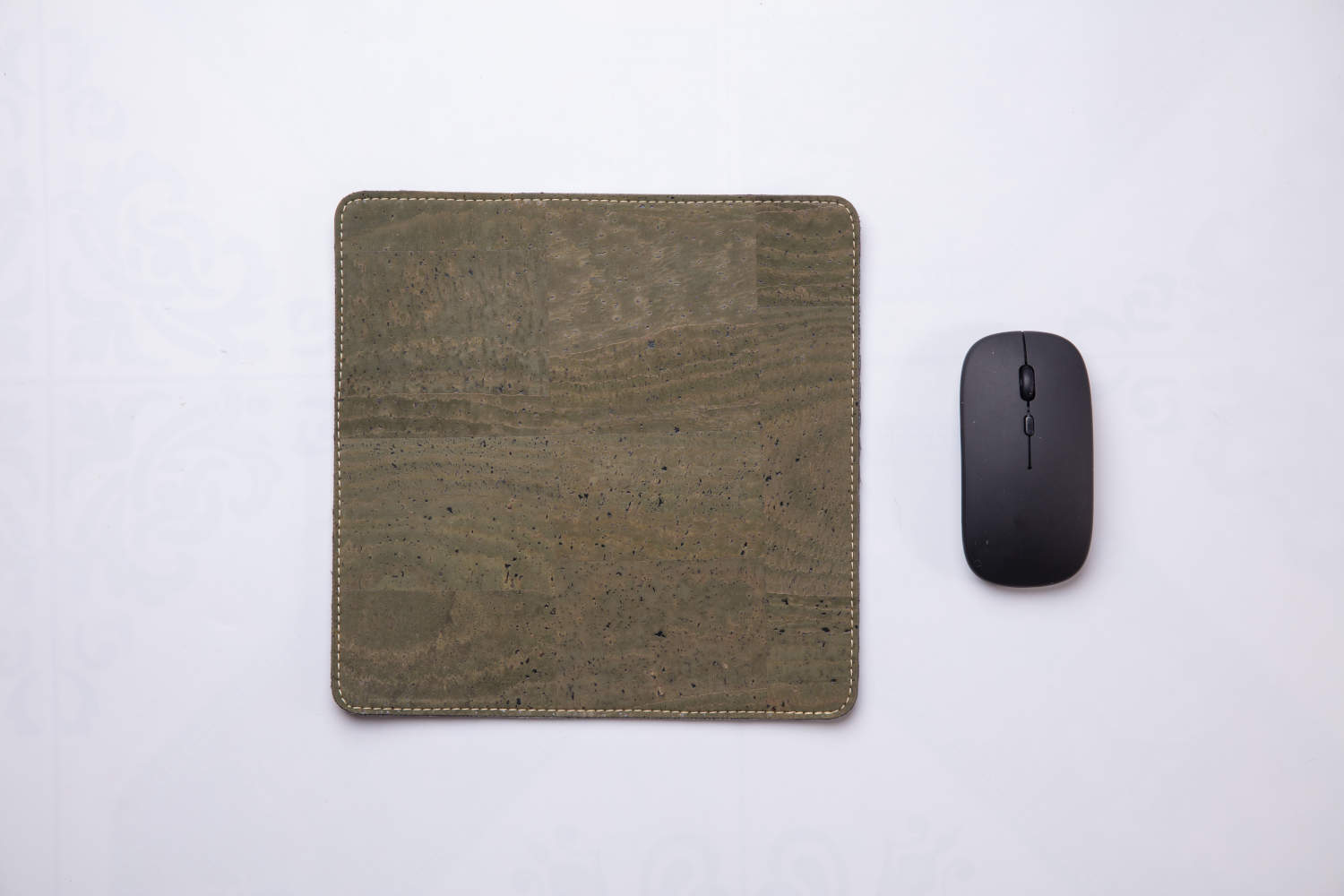 Green travel mousepad next to wireless mouse against white background