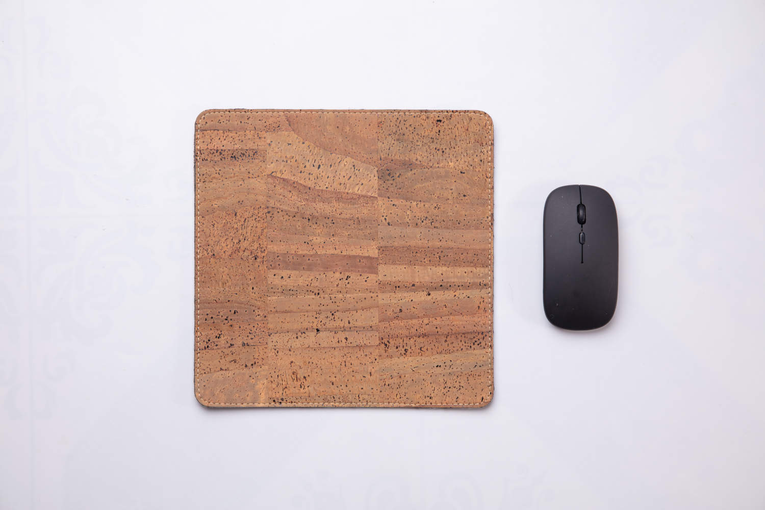 Tan travel mousepad next to wireless mouse against white background